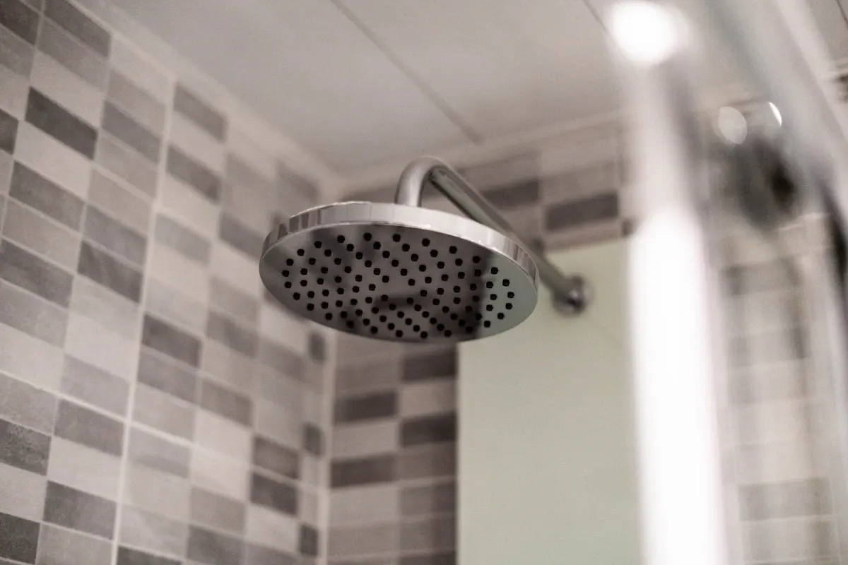 Close view of a wall-mounted shower head and tiled wall